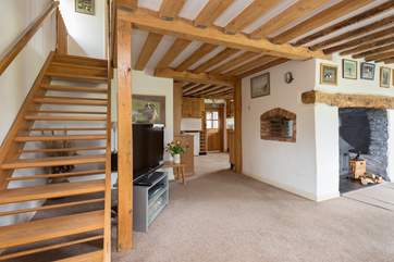 This photograph shows the layout of the kitchen beyond the living-room, as well as the open-tread stairs to the first floor. There is a second staircase at the other end of the house.