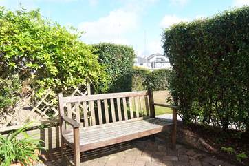 The patio outside the sitting-room is screened by hedges.