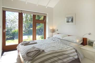 The comfortable double bedroom has a king-size bed and a glass door opening onto the garden decking.
