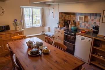 The attractive kitchen has a farmhouse-style dining-table and views over the cove.