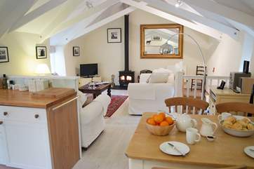 The living-room has an open beamed ceiling, lime-washed wood floors and a cosy wood-burner.