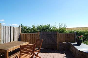 There is a big wooden table, bench and chairs for outdoor meals.