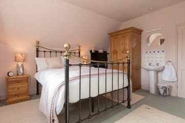 The main bedroom has a traditional brass and iron bed and plenty of storage space.