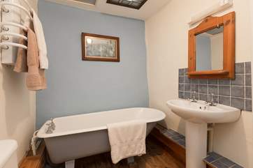 The bathroom has a traditional roll-top bath.