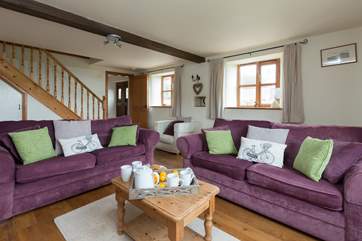 There is a spacious living-room with comfortable sofas and a wood-burner effect electric stove in the fireplace.