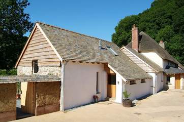 The exterior of Otter's Holt, next to the Owners' thatched home.