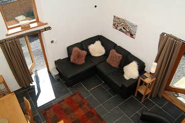 A view of the sitting/dining-room from the top of the staircase. This high ceilinged room has a wonderful wood-burning stove to keep you extra snug whatever time of year you come here on holiday.