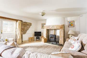 The lovely sitting-room with comfy sofas around the wood-burner.