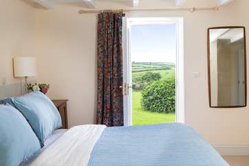 The master bedroom enjoys views from the window and door onto the garden and countryside beyond.