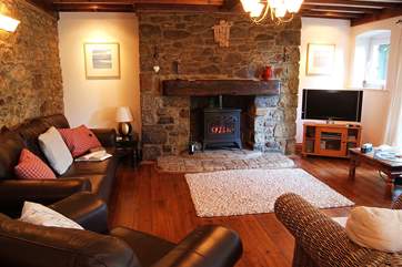 The sitting/dining-room has comfy seating for all around the stone fireplace.