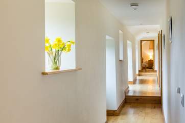 The hallway with windows overlooking the courtyard to the left and bedrooms to the right; there are a couple of internal steps in the hall, well spread out.