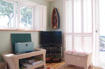 The TV and DVD player are tucked into a corner, next to the door out to the attached deck area.