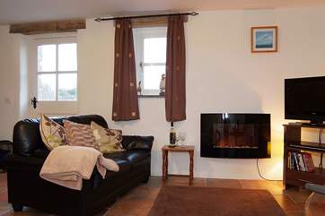 The comfy living-room includes a wall-mounted fire, great for those cooler evenings.