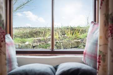 The sitting/dining-room looks out across the enclosed front courtyard to the fields and reservoir beyond.