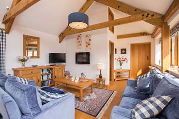 The living area has two lovely deep sofas and French windows out to the patio and garden beyond.