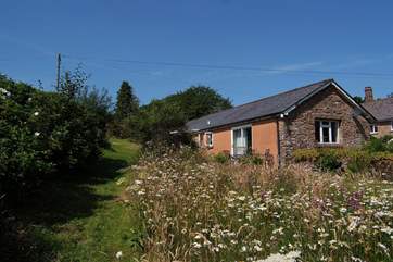 There is a very private patio overlooking the lovely garden with its wildflower borders, and then views all the way down the valley beyond.
