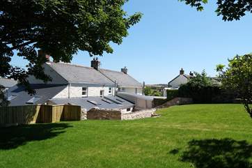 Looking across the lawn, the rural landscape surrounding the village can be seen between neighbouring rooftops.