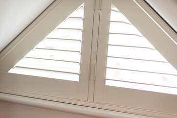 Shutters dress the triangular window in Bedroom 2.