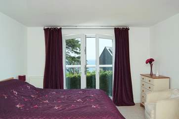 Bedroom 2 has a king-size bed, and double glass doors with a Juliet balcony overlooking the bay.
