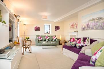 The spacious sitting/dining-room looks out across the terrace to the water beyond.