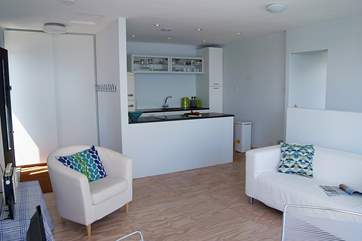 The light open plan living-room with the kitchen at the rear and doorway to the twin bedroom and shower-room (a new wood-burner for has been added).