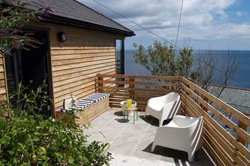 The outside 'deck' includes a padded bench and chairs for relaxing, there is also an outside tap to wash off your beach gear and wetsuits.