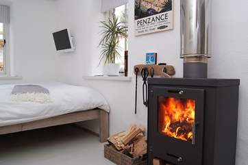 The wood-burner is set next to the comfortable double bed.