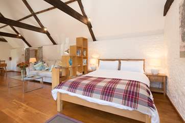The bed is at the far end of the open plan living space, with clever use of the bookshelf to make it feel tucked away.