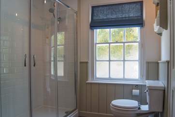 The spacious bathroom has a big corner shower cubicle.