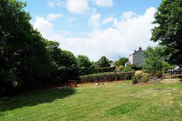 The view across the shared garden towards the Owners' cottage seen amongst the trees on the right.