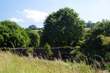 Looking over the river bank which runs alongside the cottage garden to the old stone bridge spanning the water.