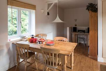 The dining-table at the end of the living-room and beyond that the stairs down to the ground floor bedrooms and bathroom.