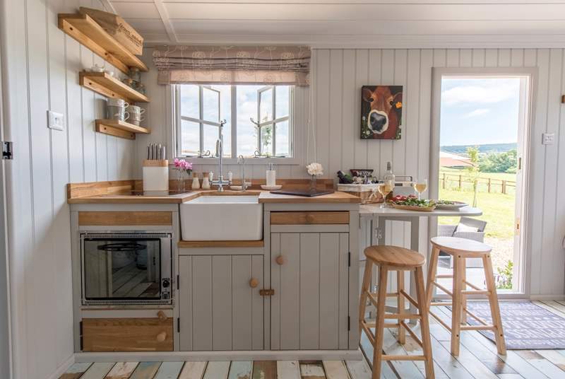 The kitchen window looks out over the patio and farmland beyond. There is a two-ring hob and mini oven and a gas fridge.