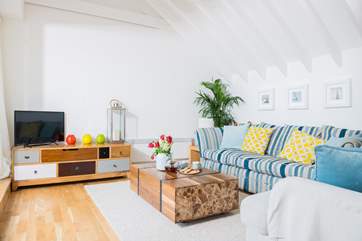 The vaulted living-room is tastely furnished with a comfy sofa and solid wood furniture.