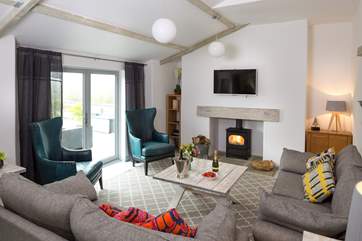The comfy sofas and stylish armchairs flank the wood-burner. There is a short bannister to one side of the steps leading down into this room.