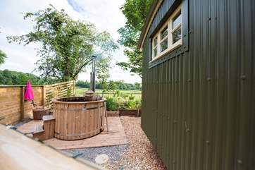 The wood-fired hot tub is positioned in a private spot to the side of the hut but fully screen fenced for privacy.