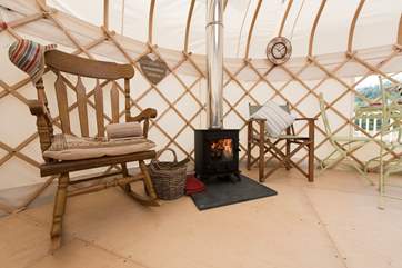There is a rocking chair positioned next to the wood-burner.