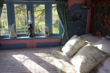 The sun streams through the window into the beautiful bedroom.