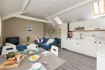 Another view of the open plan living area with the kitchen to one side, a dining-table and plenty of comfortable seating too.