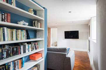 The opposite side of the chimney stack houses bookshelves laden with books and games.
