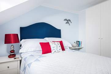Soft furnishings with a splash of red and blue bring a freshness to this comfortable bedroom.