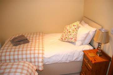 The beds are laid in an 'L' shape and each have their own bedside table and lamp.