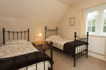 The twin room features cast iron bedsteads and overlooks the gardens.