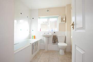 The bright modern bathroom features a shower over the bath.