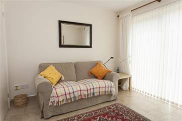 Family room with sofa, TV and doors to patio and rear garden.