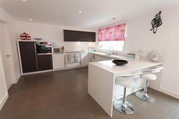 The contemporary kitchen benfits from a breakfast bar and is fully equipped.
