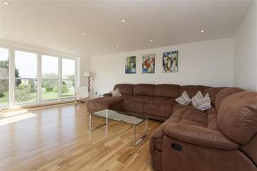 The spacious living room, with generous seating, has doors leading to a large decked balcony.