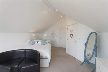 The master bedroom is spacious, with a sofa to sink into whilst you enjoy the views from the large window facing the sea.