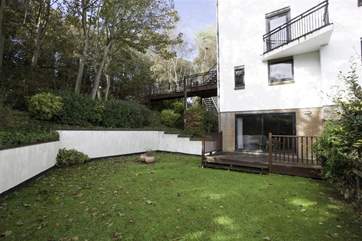 Large lawned area and decking at the rear of apartment, with access from the living room