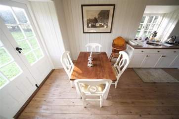 The dining and living area has doors open to the lovely grounds at the rear